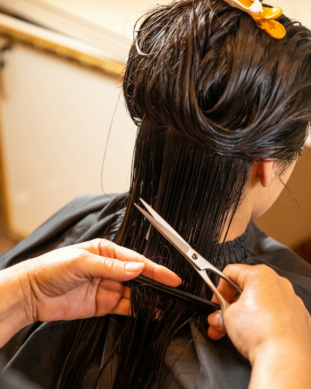 Coiffeuse en train de couper des cheveux bruns aux ciseaux